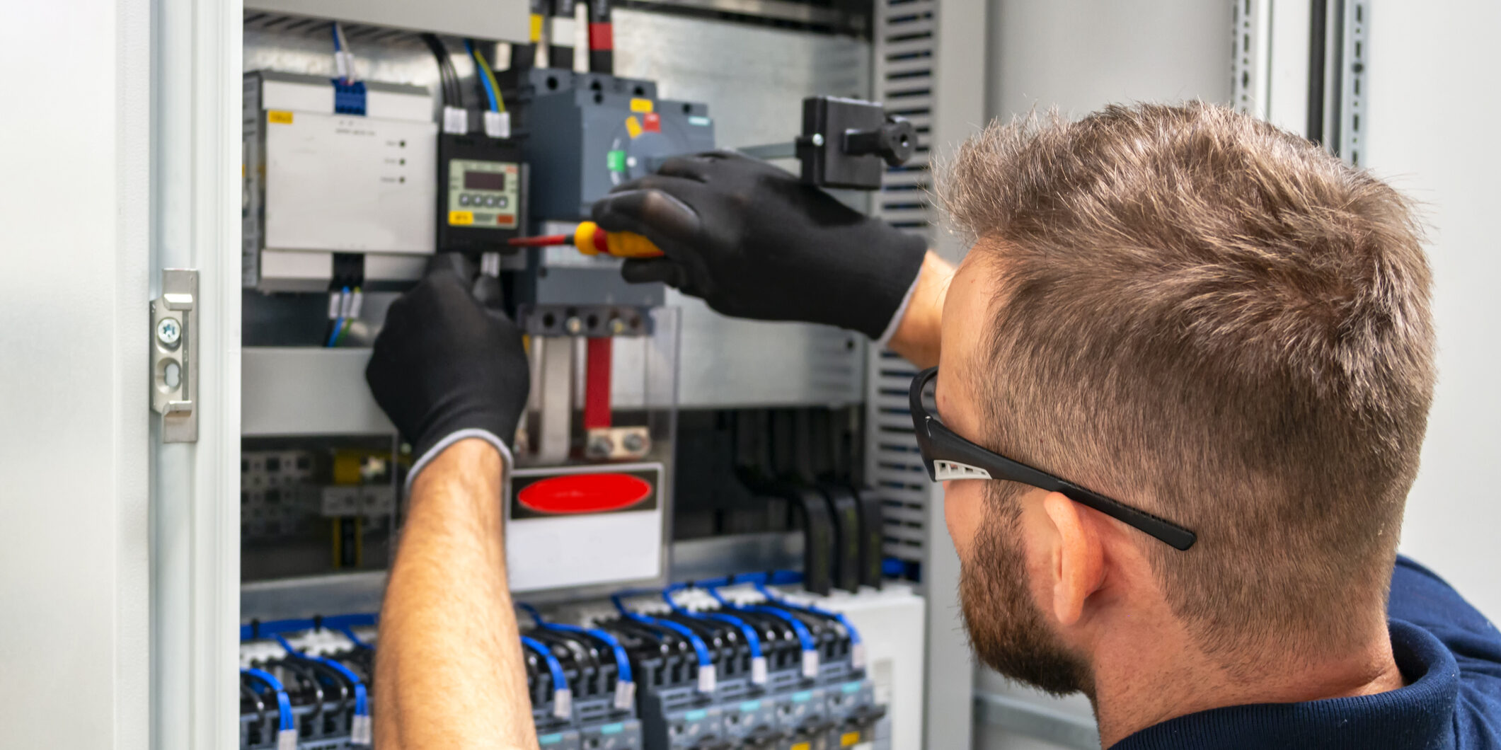 Photo of an electrician working at distribuition board.